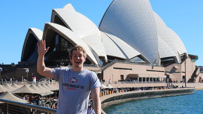 Student waving in front of Sydney Opera House